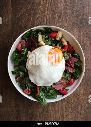 Pochierte Eier mit Speck, Salat, Käse und Brot zum Frühstück. Ökologische Lebensmittel. Stockfoto