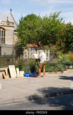Street artist Radierung auf Holz mit einer Lupe mit der Nutzung der Sonne, Hohe Straße, Glastonbury, Großbritannien Stockfoto