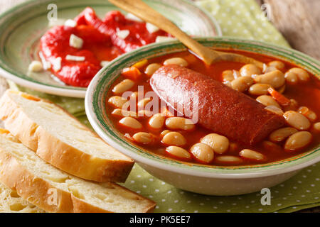 (Pasulj grah) Bohnensuppe mit Wurst mit Brot und Paprika in der Nähe serviert auf einem Teller auf den Tisch. Horizontale Stockfoto