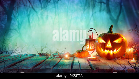 Halloween - Jack O'Lanterns und Kerzen auf dem Tisch in der nebligen Nacht Stockfoto