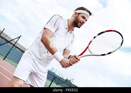 Profi-Tennisspieler tut ein Kick-Tennis auf dem Tennisplatz an einem sonnigen Sommermorgen. Das ist in der Sportswear gekleidet. Stockfoto