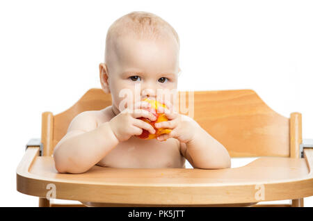 Cute Baby girl peach Essen während der Sitzung in Hochstuhl auf weißem Hintergrund Stockfoto