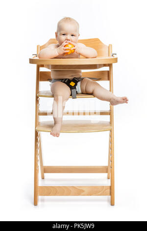 Cute Baby girl peach Essen und lächelnd, während in der hohen Stuhl über weiße Sitzen Stockfoto