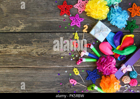 Pfeifen, Ballons, Geschenke, Kerzen, Dekoration auf alten hölzernen Hintergrund. Konzept der Kindergeburtstag. Ansicht von oben, flach. Stockfoto