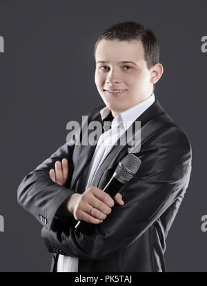 Zuversichtlich, dass junge Unternehmer mit Mikrofon auf schwarzem Hintergrund Stockfoto