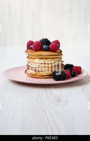 Pfannkuchen mit Beeren auf einem Rosa die Platte über der weißen Holz- Hintergrund, Seitenansicht. Stockfoto