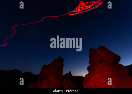 Licht Malen und Zeichnen mit roten Taschenlampe, außerirdisches Raumschiff fliegen in über den roten Felsen von der vulkanischen Landschaft auf den Teide Nationalpark in der Dämmerung, Tene Stockfoto