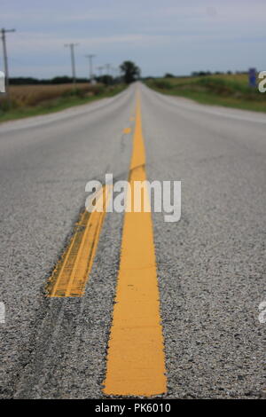 Auf der Suche der Mitte gelbe Linie von einer Geraden und lange Landstraße in ländlichen Marengo, Illinois, McHenry County. Stockfoto