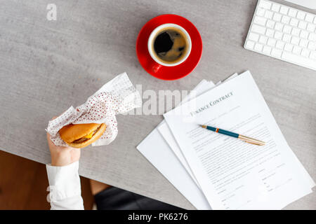 Young Business Frau Burger essen am Schreibtisch Stockfoto