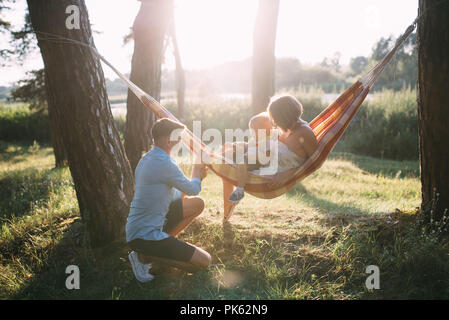 Junge sympathische Familie - Mutter, Vater und Sohn die Erholung in der Natur, in einer Hängematte. Stockfoto