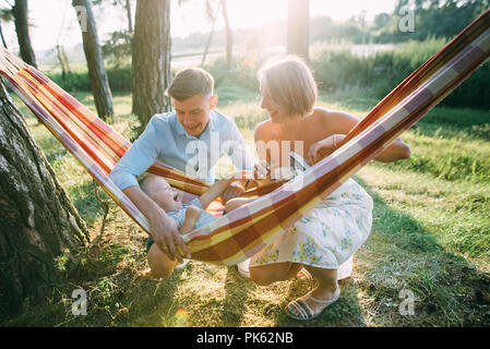 Junge sympathische Familie - Mutter, Vater und Sohn die Erholung in der Natur, in einer Hängematte. Stockfoto