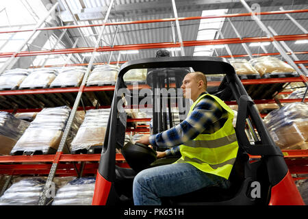 Männliche Arbeiter fahren Gabelstapler Lader an Lager Stockfoto