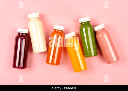 Flaschen von bunten Smoothies oder Säfte auf rosa Hintergrund. Flach Stil. Stockfoto