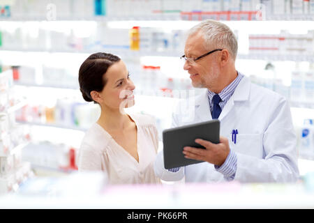 Apotheke und Kunden mit Tablet-PC in der Apotheke Stockfoto