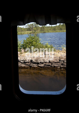 Göta kanal, Bootsfahrt entlang einer idyllischen Wasserstraße in Schweden, Blick auf die umliegende Landschaft aus einem Fenster Sandön an Bord von Fahrgastschiffen befindlichen Personen Stockfoto