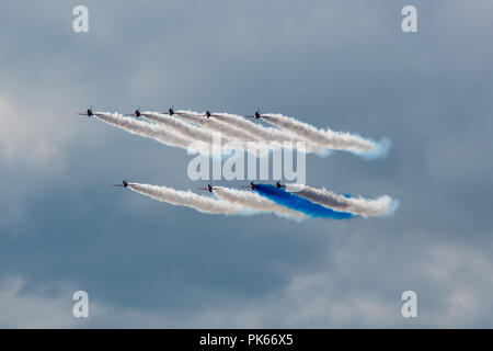 Eine einsame blaue Rauchfahne kontrastiert mit der dicken weißen Rauch der anderen acht Red Arrows Hawk Jets Stockfoto