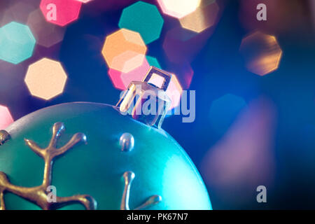 Eine große Glaskugel mit einem Muster von Schneeflocken. Im Hintergrund verschwommen Lichter von einem Weihnachtsbaum. Boke. Weihnachten Spielzeug in der Weihnachtszeit Lametta. Stockfoto
