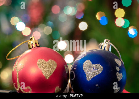 Eine große Glaskugel mit einem Muster von Schneeflocken. Im Hintergrund verschwommen Lichter von einem Weihnachtsbaum. Boke. Weihnachten Spielzeug in der Weihnachtszeit Lametta. Stockfoto
