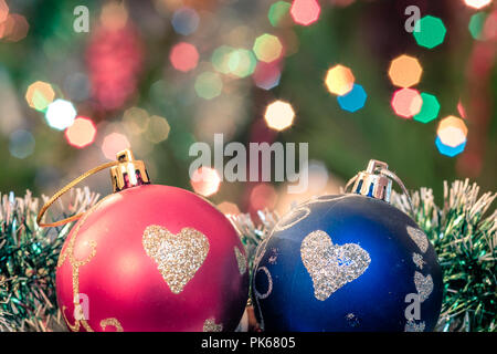 Eine große Glaskugel mit einem Muster von Schneeflocken. Im Hintergrund verschwommen Lichter von einem Weihnachtsbaum. Boke. Weihnachten Spielzeug in der Weihnachtszeit Lametta. Stockfoto
