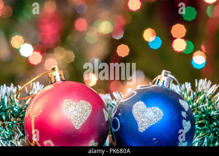 Eine große Glaskugel mit einem Muster von Schneeflocken. Im Hintergrund verschwommen Lichter von einem Weihnachtsbaum. Boke. Weihnachten Spielzeug in der Weihnachtszeit Lametta. Stockfoto