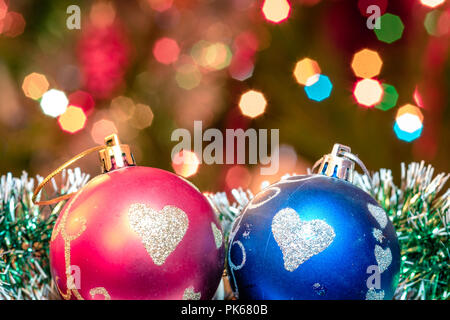 Eine große Glaskugel mit einem Muster von Schneeflocken. Im Hintergrund verschwommen Lichter von einem Weihnachtsbaum. Boke. Weihnachten Spielzeug in der Weihnachtszeit Lametta. Stockfoto