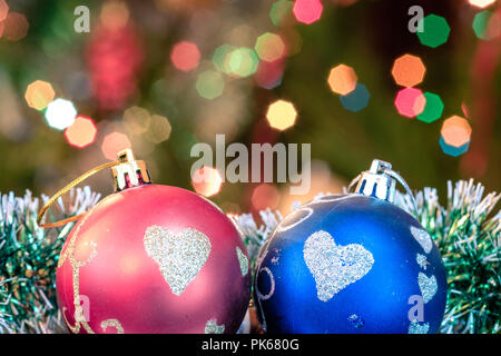Eine große Glaskugel mit einem Muster von Schneeflocken. Im Hintergrund verschwommen Lichter von einem Weihnachtsbaum. Boke. Weihnachten Spielzeug in der Weihnachtszeit Lametta. Stockfoto