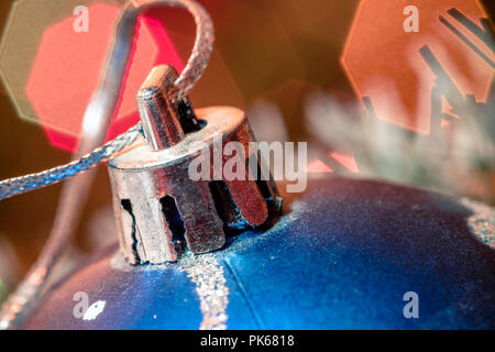 Eine große Glaskugel mit einem Muster von Schneeflocken. Im Hintergrund verschwommen Lichter von einem Weihnachtsbaum. Boke. Weihnachten Spielzeug in der Weihnachtszeit Lametta. Stockfoto