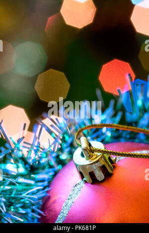 Eine große Glaskugel mit einem Muster von Schneeflocken. Im Hintergrund verschwommen Lichter von einem Weihnachtsbaum. Boke. Weihnachten Spielzeug in der Weihnachtszeit Lametta. Stockfoto