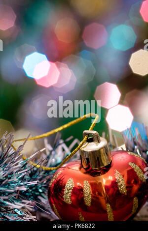 Eine große Glaskugel mit einem Muster von Schneeflocken. Im Hintergrund verschwommen Lichter von einem Weihnachtsbaum. Boke. Weihnachten Spielzeug in der Weihnachtszeit Lametta. Stockfoto