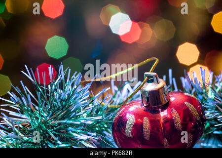 Eine große Glaskugel mit einem Muster von Schneeflocken. Im Hintergrund verschwommen Lichter von einem Weihnachtsbaum. Boke. Weihnachten Spielzeug in der Weihnachtszeit Lametta. Stockfoto
