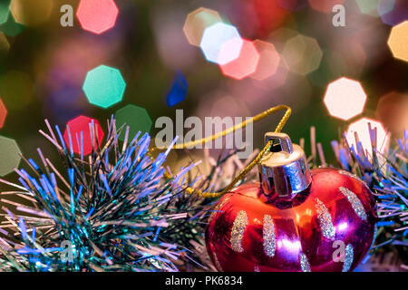 Eine große Glaskugel mit einem Muster von Schneeflocken. Im Hintergrund verschwommen Lichter von einem Weihnachtsbaum. Boke. Weihnachten Spielzeug in der Weihnachtszeit Lametta. Stockfoto