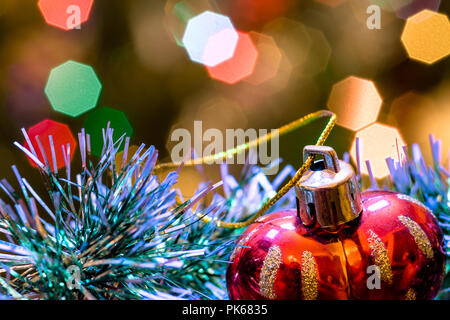 Eine große Glaskugel mit einem Muster von Schneeflocken. Im Hintergrund verschwommen Lichter von einem Weihnachtsbaum. Boke. Weihnachten Spielzeug in der Weihnachtszeit Lametta. Stockfoto