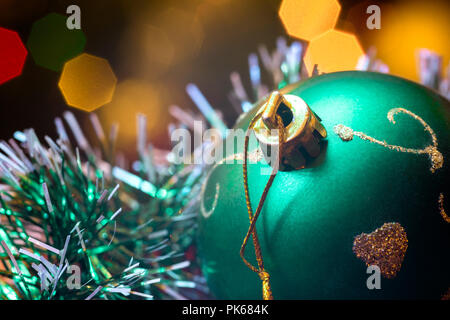 Eine große Glaskugel mit einem Muster von Schneeflocken. Im Hintergrund verschwommen Lichter von einem Weihnachtsbaum. Boke. Weihnachten Spielzeug in der Weihnachtszeit Lametta. Stockfoto