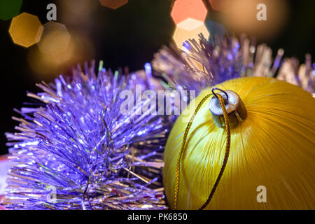 Eine große Glaskugel mit einem Muster von Schneeflocken. Im Hintergrund verschwommen Lichter von einem Weihnachtsbaum. Boke. Weihnachten Spielzeug in der Weihnachtszeit Lametta. Stockfoto