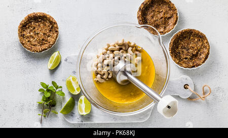 Banner der Vorbereitung von vegan paleo Creme von Cashew-nüssen und Mango Püree für mini Torten aus Nüssen und Termine. gesunde Alternative Rohkost mit Han Stockfoto