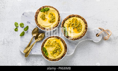 Banner von vegan raw mini Torten aus Nüssen und Termine mit Cashew Creme vom Mango Püree mit Limettensaft und Samen von Passionsfrucht. gesunde Alternative Stockfoto