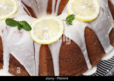 Ganze Zitrone Frischkäse bundt Cake mit Scheiben von frischen Zitronen und Minze. Extrem flache Tiefenschärfe mit selektiven Fokus in der Mitte der Torte Stockfoto