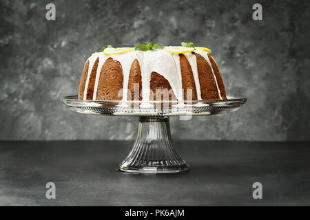 Ganze Zitrone Frischkäse bundt Cake mit Scheiben von frischen Zitronen und Minze. Extrem flache Tiefenschärfe mit selektiven Fokus auf Kuchen. Kostenlose spa Stockfoto