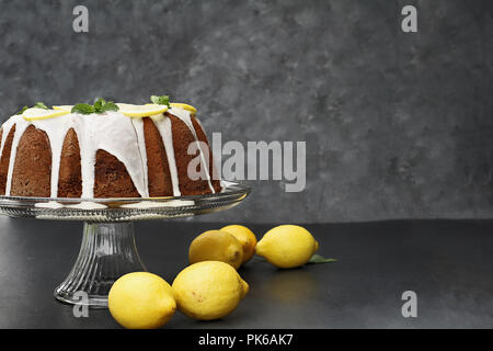 Ganze Zitrone Frischkäse bundt Cake mit Scheiben von frischen Zitronen und Minze. Extrem flache Tiefenschärfe mit selektiven Fokus auf Kuchen. Kostenlose spa Stockfoto