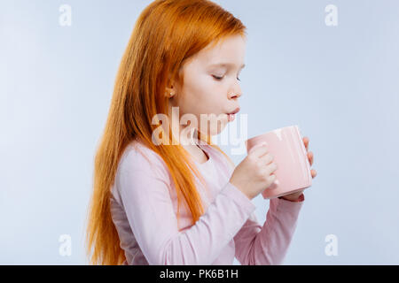 Nette junge Mädchen bläst an der Tasse Tee Stockfoto