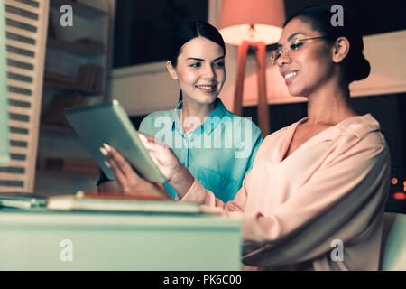 Lächelnde Mädchen in Gläsern etwas auf Tablet Stockfoto