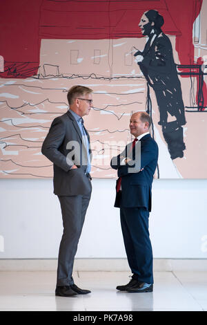 10 September 2018, Berlin: 10.09.2018, Berlin: Dietmar Bartsch (l), Vorsitzender der Parlamentarischen Gruppe der Partei Die Linke, und Olaf Scholz (SPD), Bundesminister der Finanzen, sprechen in einem Korridor in den Deutschen Bundestag vor der Sitzung der SPD-Fraktion im Bundestag. Im Hintergrund hängt ein Gemälde von Susanne Ludwig, die zeigt Marie Juchacz während der ersten Rede einer Frau, die auf die Weimarer Nationalversammlung 1919. Foto: Bernd von Jutrczenka/dpa Stockfoto