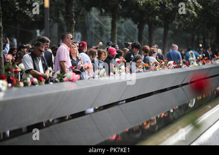 New York, USA. 11 Sep, 2018. Menschen würdige Opfer neben Platten, auf denen die Namen der 11 Opfer um der Nord Pool an der Nationalen September 11 Memorial und Museum in New York, USA, Sept. 11, 2018 eingeschrieben waren. Tausende von Menschen kamen hier am Dienstag zu merken, die Opfer der Terroranschläge vom 11. September, die vor 17 Jahren passiert ist und Tausende von Menschenleben. Credit: Wang Ying/Xinhua/Alamy leben Nachrichten Stockfoto