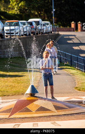 Vereinigtes Königreich, England, Yorkshire, Filey, Promenade, Kinder essen Eis neben Himmelsrichtungen Brunnen Stockfoto