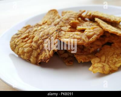 Gebratenen tempeh in einer weißen Platte auf der Holzoberfläche. Stockfoto