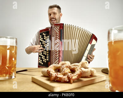 Mann in Traditionelle bayerische Kleidung spielt Akkordeon. Deutschland, Bayern, Oberbayern. Die jungen Glücklich lächelnde Mann im traditionellen österreichischen und bayerischen Kostüm Pub oder Studio. Die Feier, Oktoberfest, festival Konzept Stockfoto