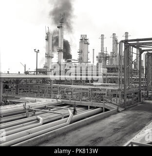 1960, historische, Außenansicht eines riesigen Ölraffinerie in der Wüste in Saudi Arabien, zeigt eine Masse von Pipelines und brennenden oder brennenden Türme. Stockfoto