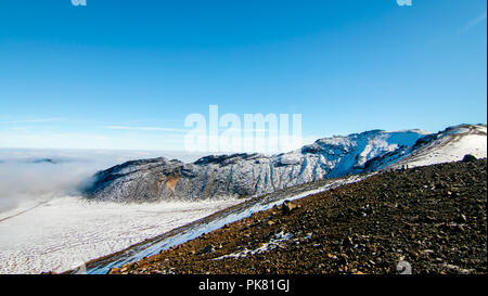 Vulkanischen Felsen Landschaft über den Wolken, Klettern von South Crater zu Red Crater, Blick auf die schneebedeckten Vulkanberge im Tongariro Neuseeland Stockfoto