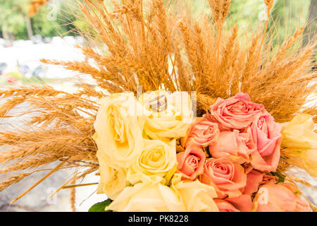 Trauringe auf Rosen Bouquet und Weizenähren Stockfoto