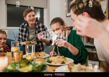 Freunde sind in einer Party zu Hause. Sie werden lachen, beim Essen Spaghetti Carbonara. Stockfoto